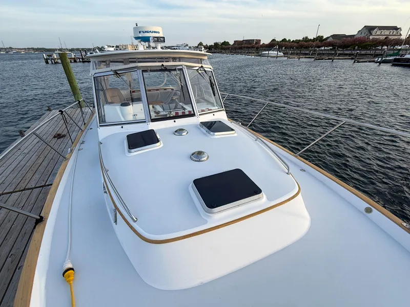 Slide: The Image of 2002 Legacy 34 Express yacht docked by the water, showcasing sleek design and spacious deck. - 46