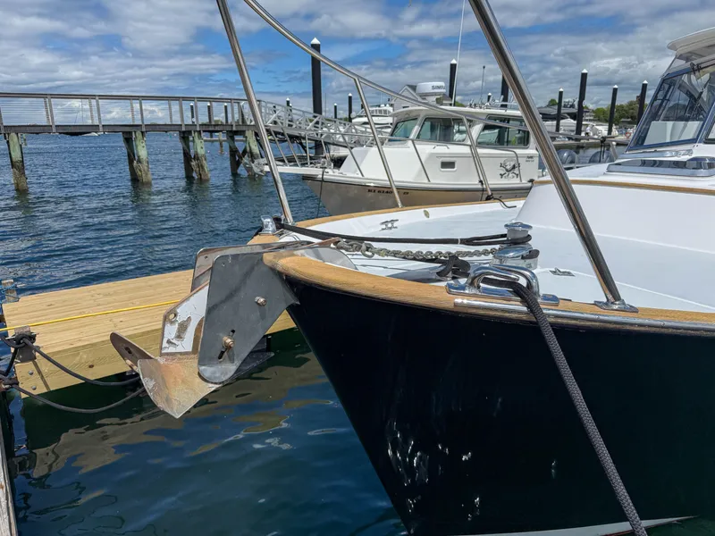 Slide: The Image of 2002 Legacy 34 Express boat docked at marina with anchor visible. - 49