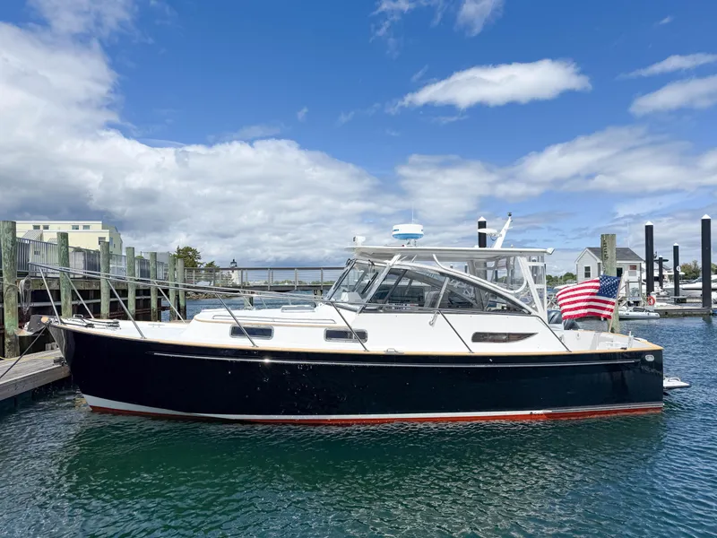 Slide: The Image of 2002 Legacy 34 Express boat docked in marina, American flag displayed, under blue sky. - 5