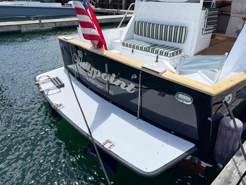 Slide: The Image of 2002 Legacy 34 Express boat docked, featuring striped seating and American flag. - 7