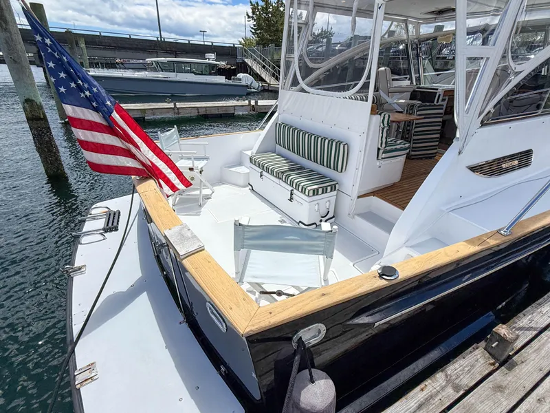 Slide: The Image of Legacy 34 Express 2002 boat with American flag, docked, featuring striped seating and open deck. - 8