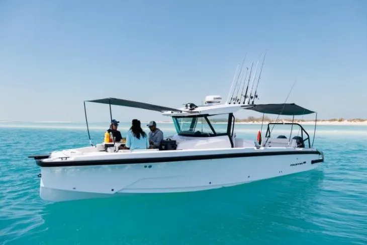 Slide: The Image of 2027 Axopar 29 CCX boat cruising on clear turquoise water with passengers onboard. - 5