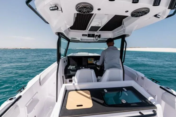 Slide: The Image of 2027 Axopar 29 CCX boat cruising on open water with a person at the helm. - 8