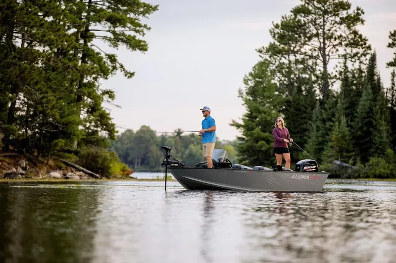 Slide: The Image of Two people fishing on a 2026 Alumacraft Classic 165 SC boat in a serene lake. - 2