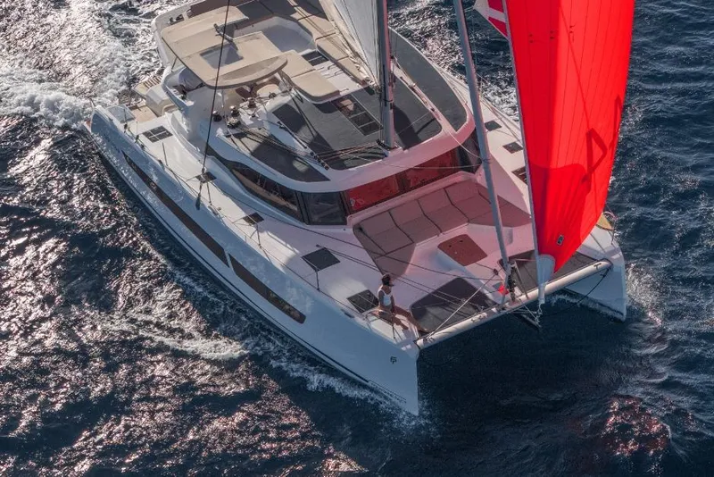 Slide: The Image of 2026 Fountaine Pajot 44 catamaran sailing with vibrant red sail on open water. - 4