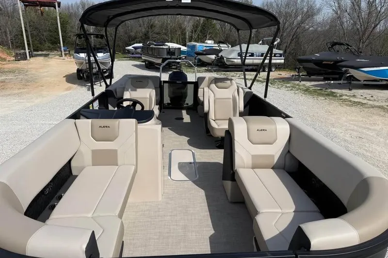 Slide: The Image of 2026 Alera 22q pontoon boat with beige seating and canopy, parked on gravel. - 16
