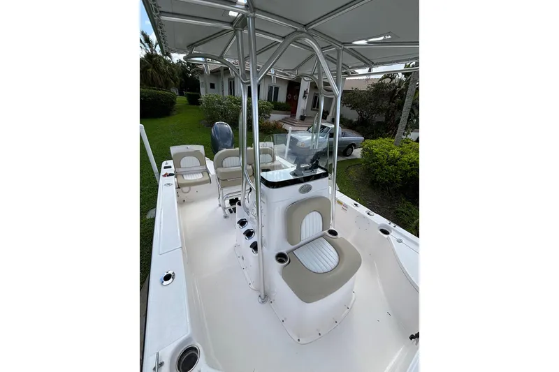Slide: The Image of 2020 Sea Born FX22 Bay boat interior with seating and console, parked near a house. - 18