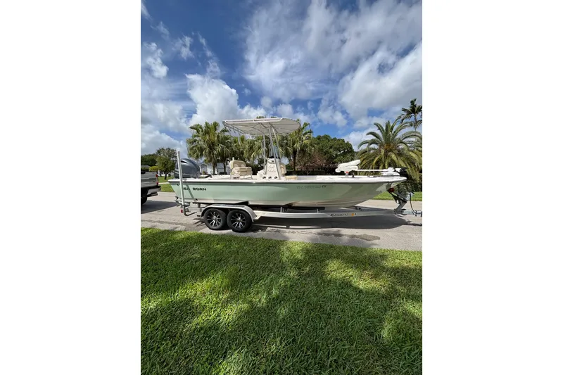 Slide: The Image of 2020 Sea Born FX22 Bay boat on trailer under a partly cloudy sky. - 2