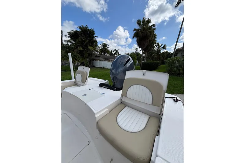 Slide: The Image of 2020 Sea Born FX22 Bay boat interior with cushioned seating and motor, under a blue sky. - 24