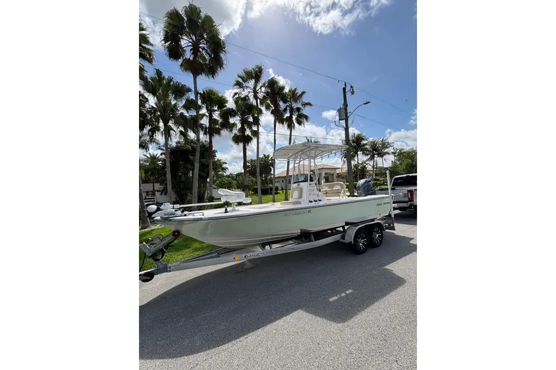 Slide: The Image of 2020 Sea Born FX22 Bay boat on trailer, parked under palm trees. - 5