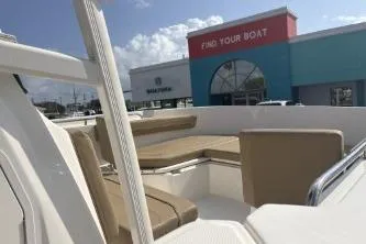 Slide: The Image of 2023 Bayliner Trophy T22CC boat with beige seating, displayed at a dealership. - 10