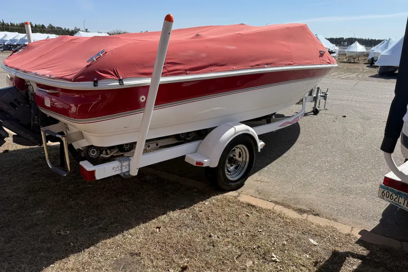 Slide: The Image of 1998 Larson Escape Delta-Conic boat with red cover on trailer, parked outdoors. - 4