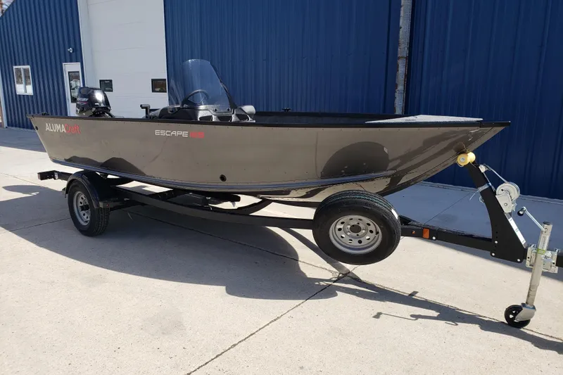 The Image of 2026 Alumacraft Escape 165 CS boat on trailer, parked outside a blue building. - 0