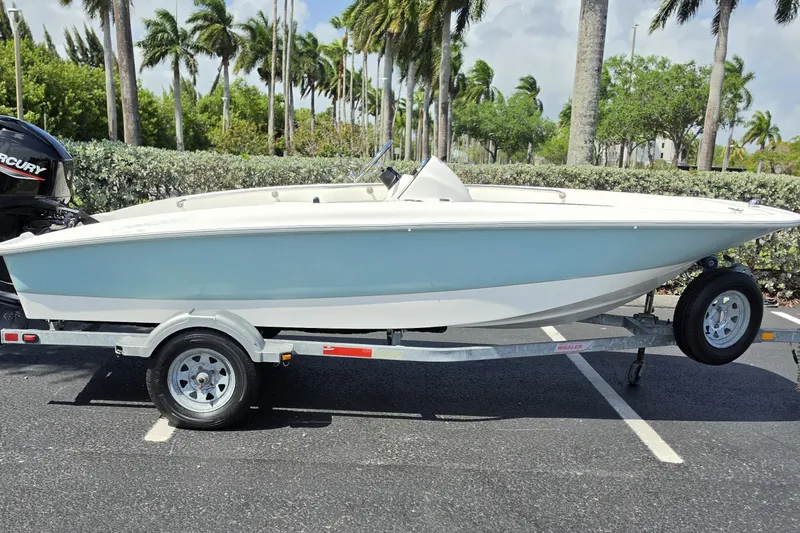 Slide: The Image of 2012 Boston Whaler 15 Super Sport boat on trailer, parked outdoors with palm trees. - 1