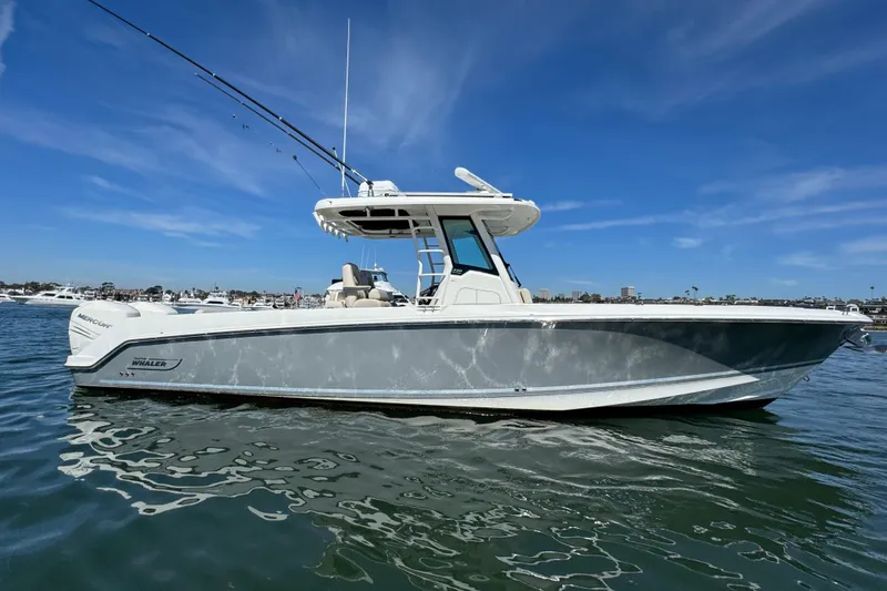 Slide: The Image of 2019 Boston Whaler 330 Outrage boat on calm water under clear blue sky. - 2
