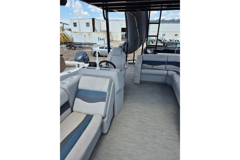 Slide: The Image of 2022 Sport Pontoons Tritoon Slide interior with seating and steering wheel, docked outdoors. - 14