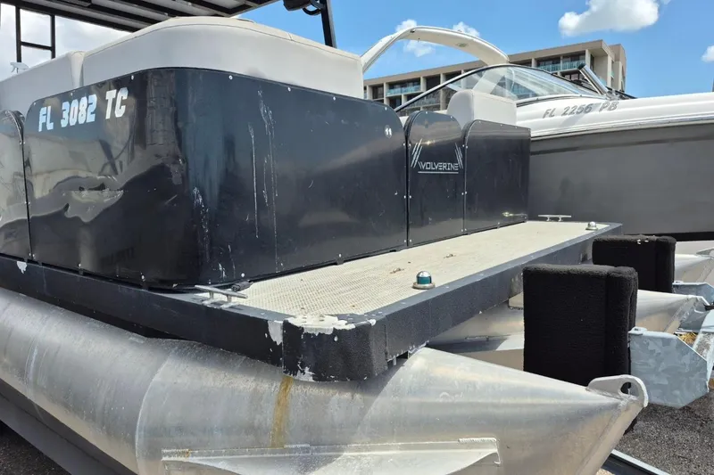 Slide: The Image of 2022 Sport Pontoons Tritoon Slide with black exterior, docked alongside another boat. - 2