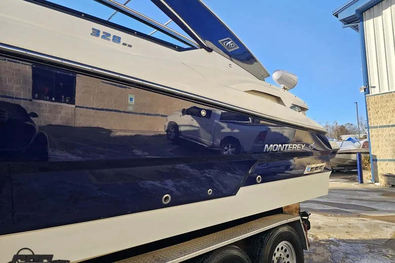Slide: The Image of 2011 Monterey 328SS Super Sport boat on trailer, reflecting surroundings, parked near a building. - 13
