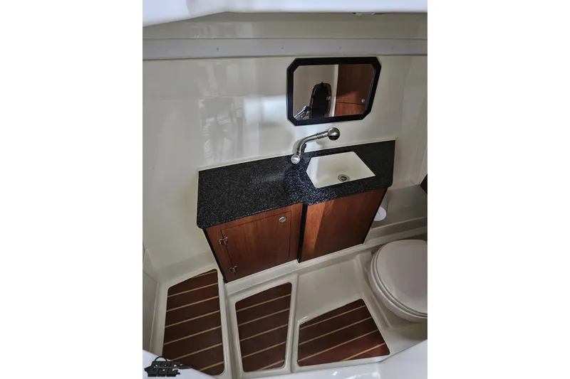Slide: The Image of 2011 Monterey 328SS Super Sport boat bathroom with sink, mirror, and wooden cabinetry. - 78