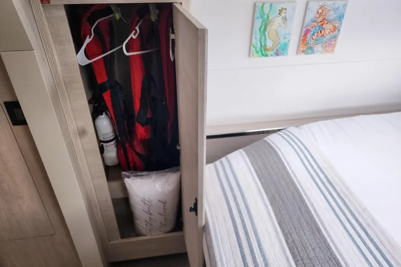 Slide: The Image of Cabin interior with open closet, red life jackets, and striped bedding on Leopard 45 yacht. - 104