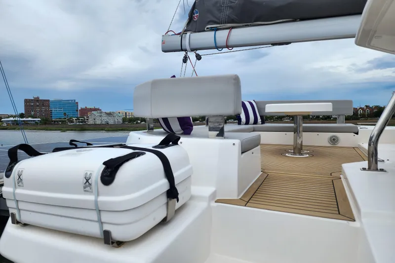 Slide: The Image of Leopard 45 catamaran deck with seating and table, 2020 model, docked by waterfront buildings. - 17