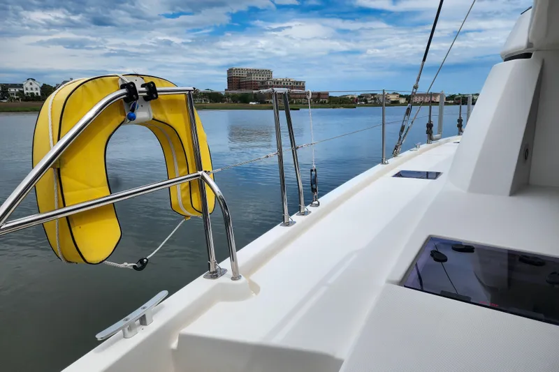 Slide: The Image of Leopard 45 catamaran deck with yellow life preserver, calm waters, and scenic shoreline. - 33
