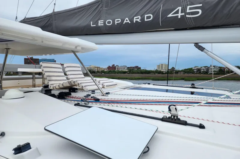 Slide: The Image of Leopard 45 catamaran deck with striped lounge chairs, cityscape in background, 2020 model. - 40
