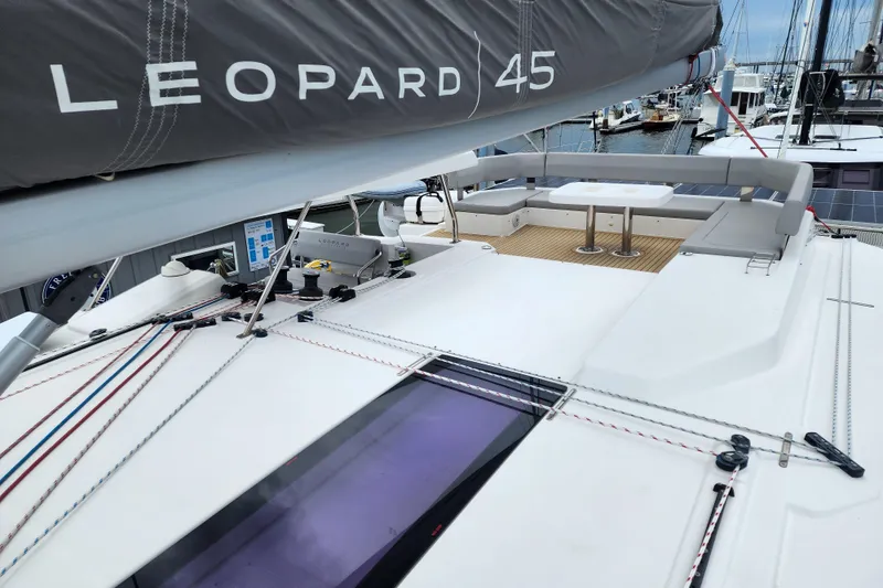 Slide: The Image of 2020 Leopard 45 catamaran deck with seating area and sail details in marina. - 48