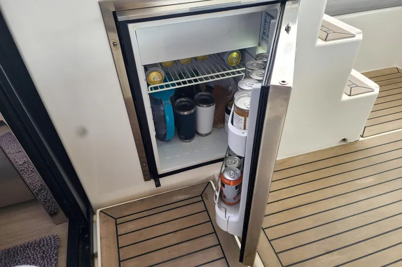 Slide: The Image of Small fridge on Leopard 45 yacht, stocked with beverages, open on teak flooring. - 92