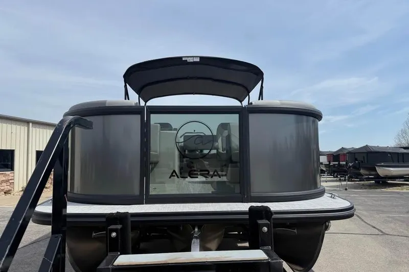 Slide: The Image of 2026 Alera 22l pontoon boat with sleek design and canopy, parked outdoors. - 2