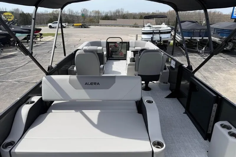 Slide: The Image of 2026 Alera 22l pontoon boat interior with seating and helm, parked outdoors. - 8