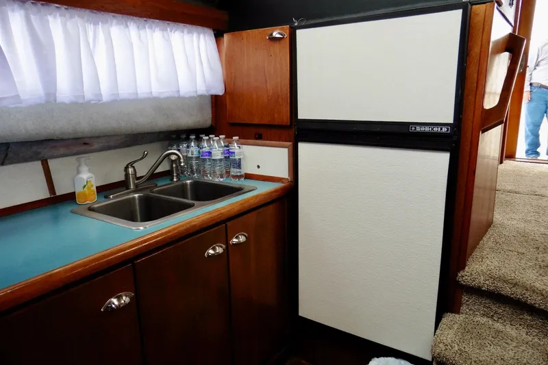 Slide: The Image of 1988 Bayliner 3888 Motoryacht kitchen with sink, fridge, and wooden cabinetry. - 11