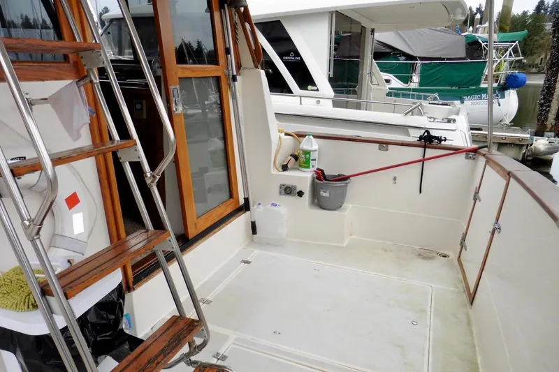 Slide: The Image of 1988 Bayliner 3888 Motoryacht deck with ladder, cleaning supplies, and docked boats in background. - 20