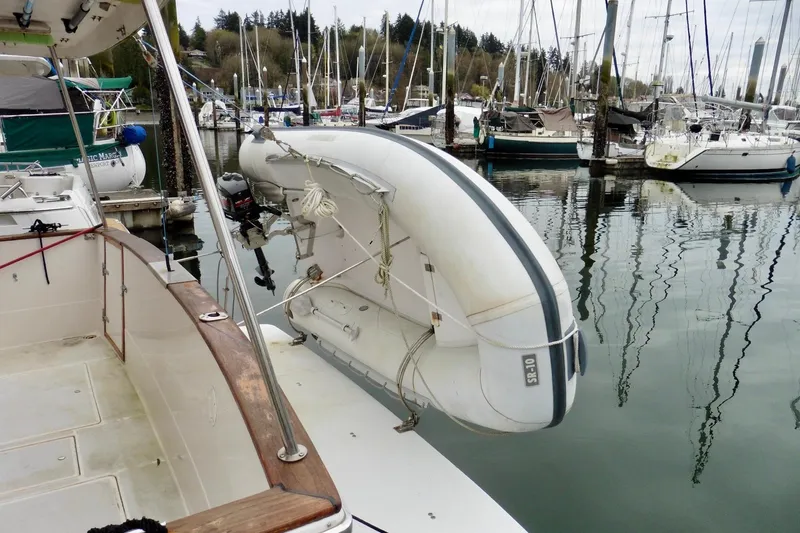 Slide: The Image of 1988 Bayliner 3888 Motoryacht with dinghy at marina, surrounded by sailboats. - 3
