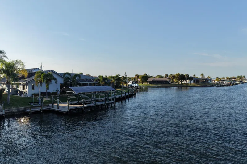 Slide: The Image of Waterfront homes with docks and palm trees along a serene canal under a clear blue sky. - 28