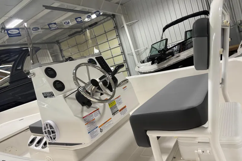 Slide: The Image of 2026 Robalo R160 Center Console boat interior with steering wheel and seating in showroom. - 6