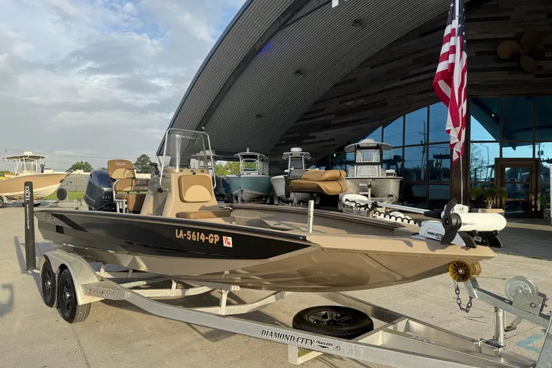 Slide: The Image of 2022 Excel 203 Bay Pro boat on trailer, parked outside showroom with American flag. - 5
