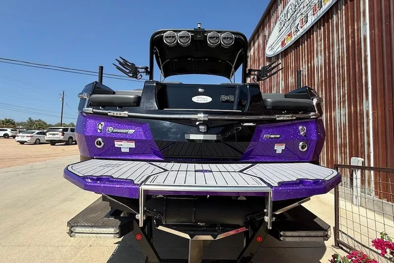 Slide: The Image of 2023 MasterCraft XStar S Piranha boat, rear view, vibrant purple finish, parked outdoors. - 3