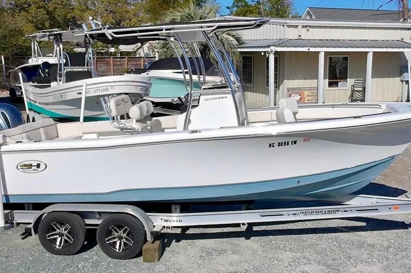 Slide: The Image of 2022 Sea Hunt Ultra 234 boat on trailer, parked outdoors near a marine shop. - 7