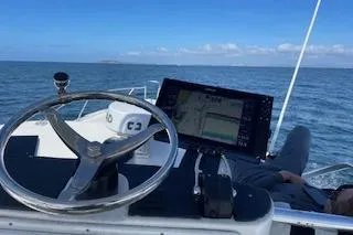 Slide: The Image of 2004 Luhrs 38 Open boat helm with navigation screen, steering wheel, and ocean view. - 15