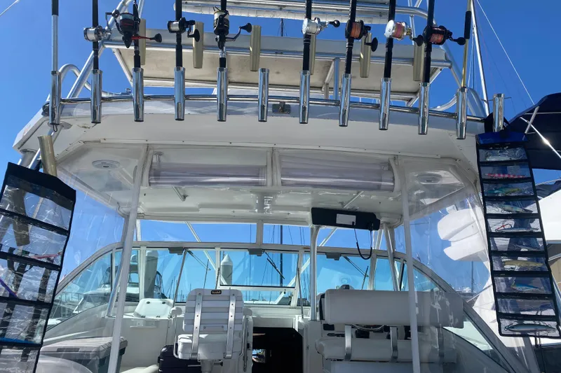 Slide: The Image of 2004 Luhrs 38 Open boat cockpit with fishing rods and seating under clear skies. - 19