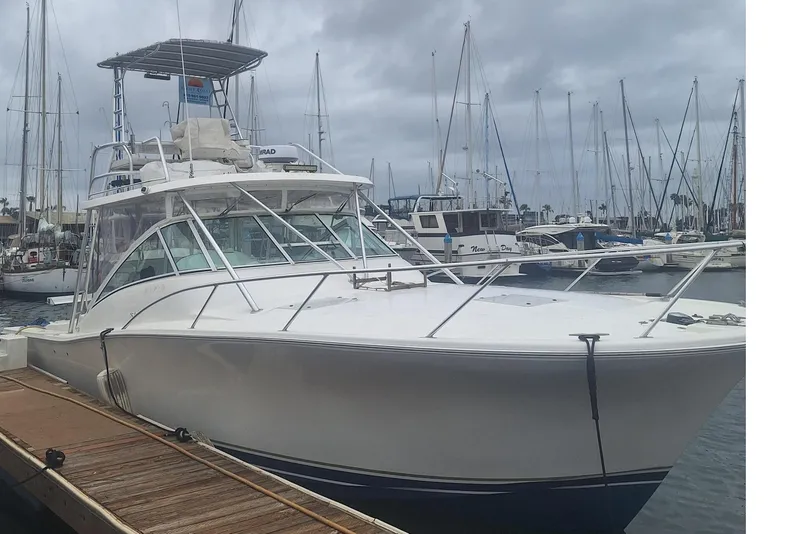 Slide: The Image of 2004 Luhrs 38 Open boat docked at marina under cloudy sky. - 2