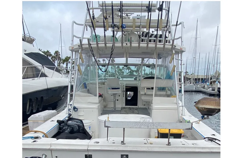 Slide: The Image of 2004 Luhrs 38 Open boat docked, featuring fishing rods and spacious cockpit area. - 22