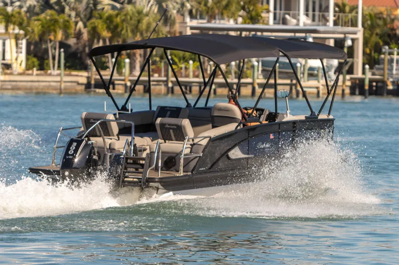 Slide: The Image of 2024 Barletta L23U pontoon boat cruising on water with canopy and outboard motor. - 15