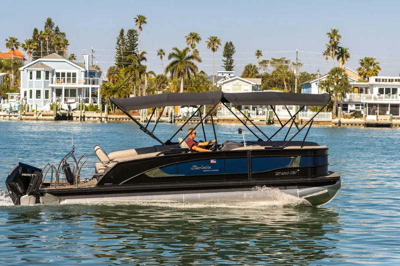 Slide: The Image of 2024 Barletta L23U pontoon boat cruising on a sunny waterfront with palm trees. - 17