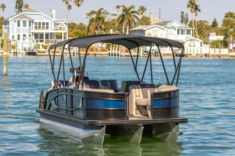 Slide: The Image of 2024 Barletta L23U pontoon boat on water, with waterfront homes and palm trees in background. - 28
