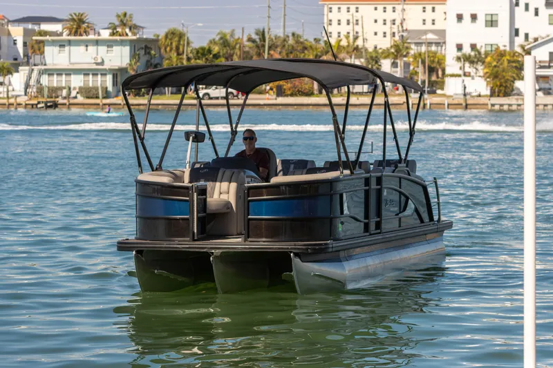 Slide: The Image of 2024 Barletta L23U pontoon boat cruising on a sunny waterfront with buildings in the background. - 3