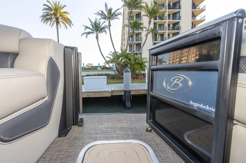 Slide: The Image of 2024 Barletta L23U pontoon boat interior near dock, palm trees, and building. - 32