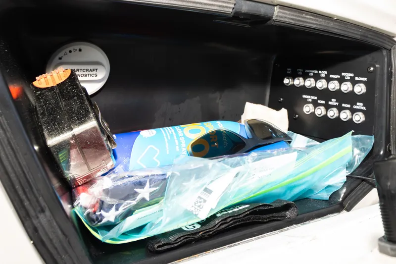 Slide: The Image of Storage compartment in 2024 Barletta L23U boat with various items and control panel. - 34