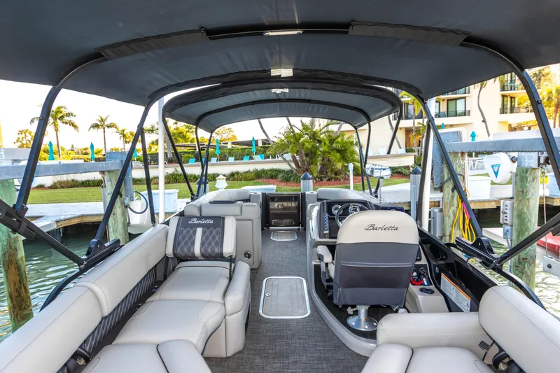 Slide: The Image of 2024 Barletta L23U pontoon boat interior with luxurious seating and helm, docked by the water. - 41